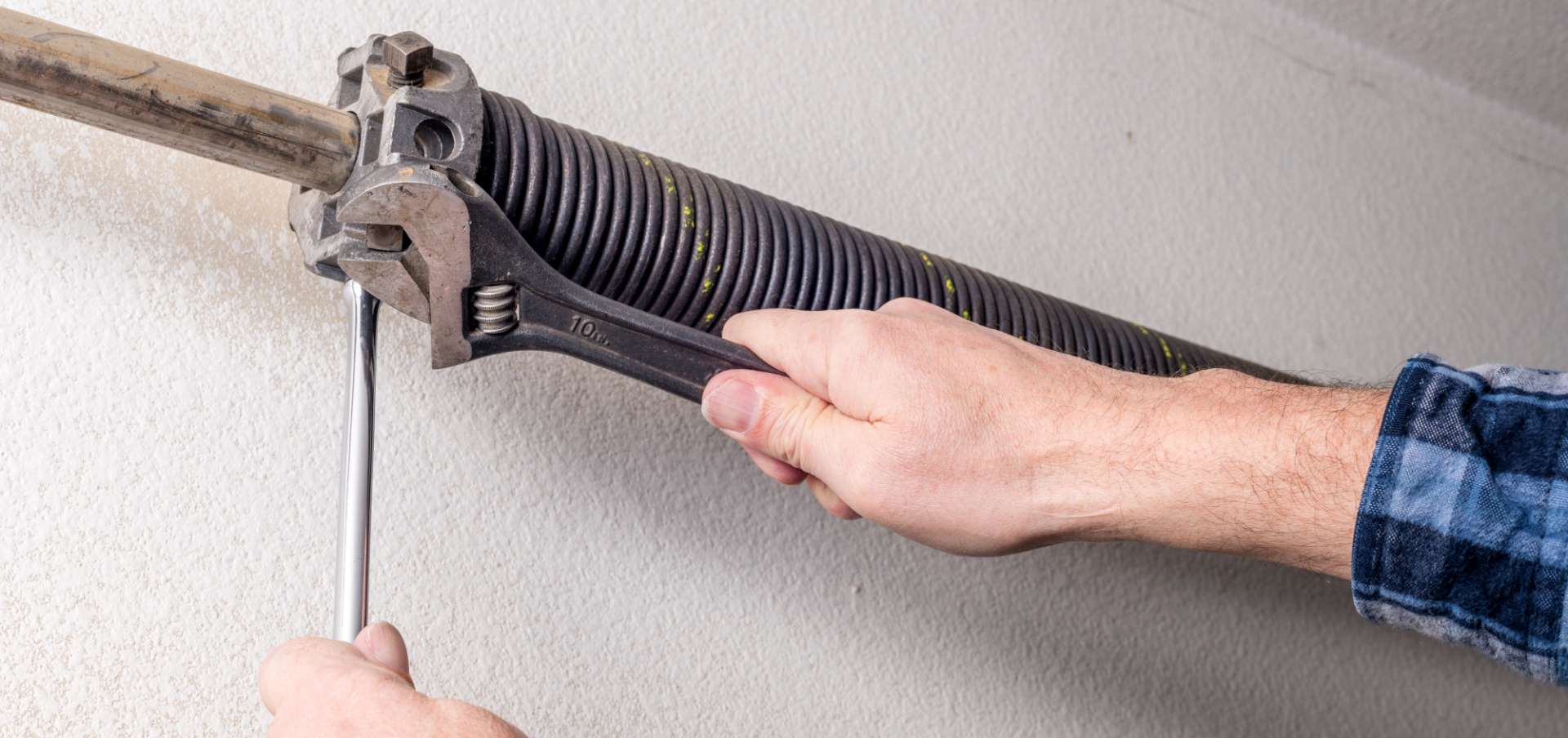 Man fixing garage spring with wrench