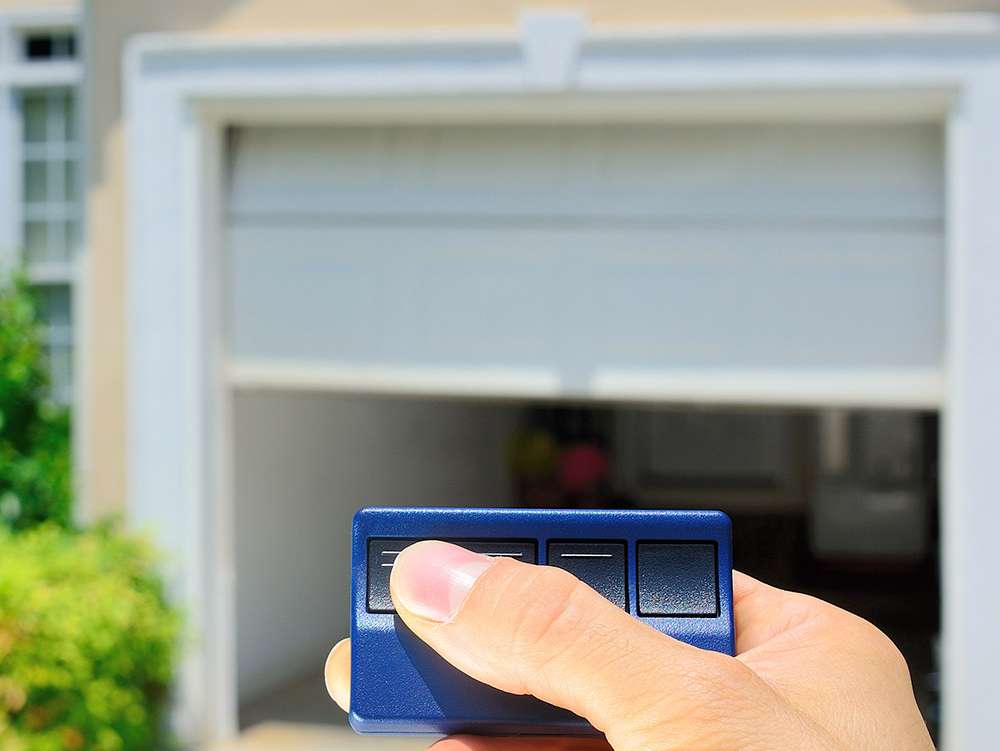 Man holding a garage door opener, opening his garage